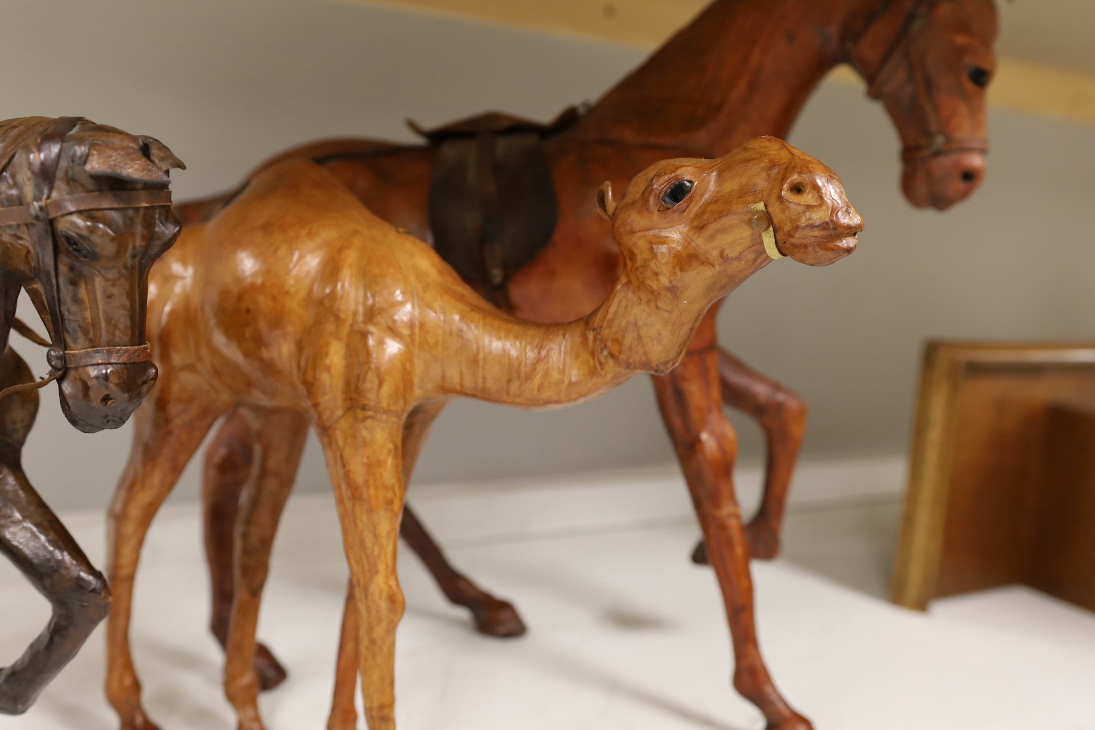Two leather worked models of horses, a rhinoceros and a camel, tallest 42cm